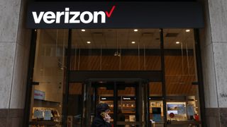 A Verizon store with a customer stood outside using their mobile cell phone